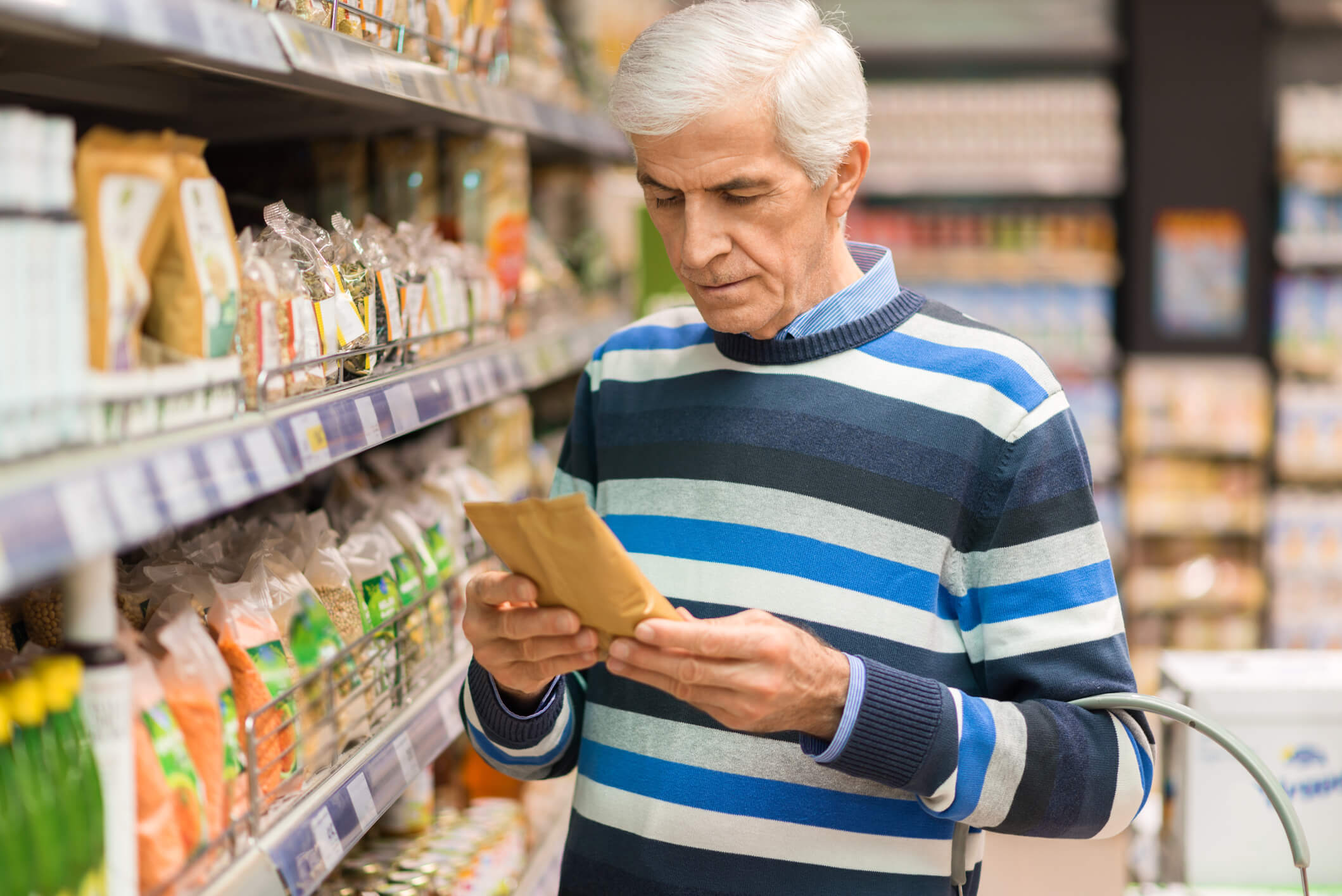 Older man examining nutrition label in grocery store