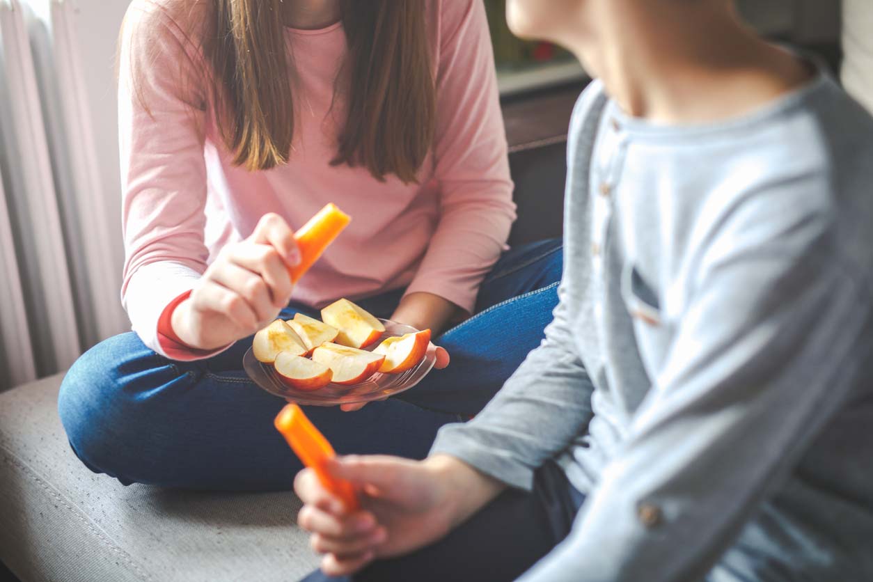 young people eating healthy crunchy snack of apples and carrots